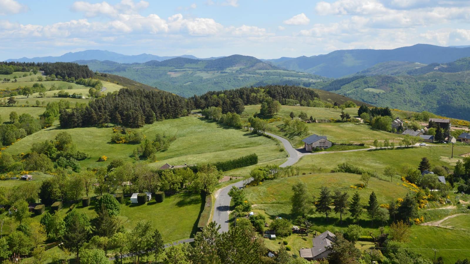 Collines verdoyantes et fermes dispersées de la campagne du Forez au printemps