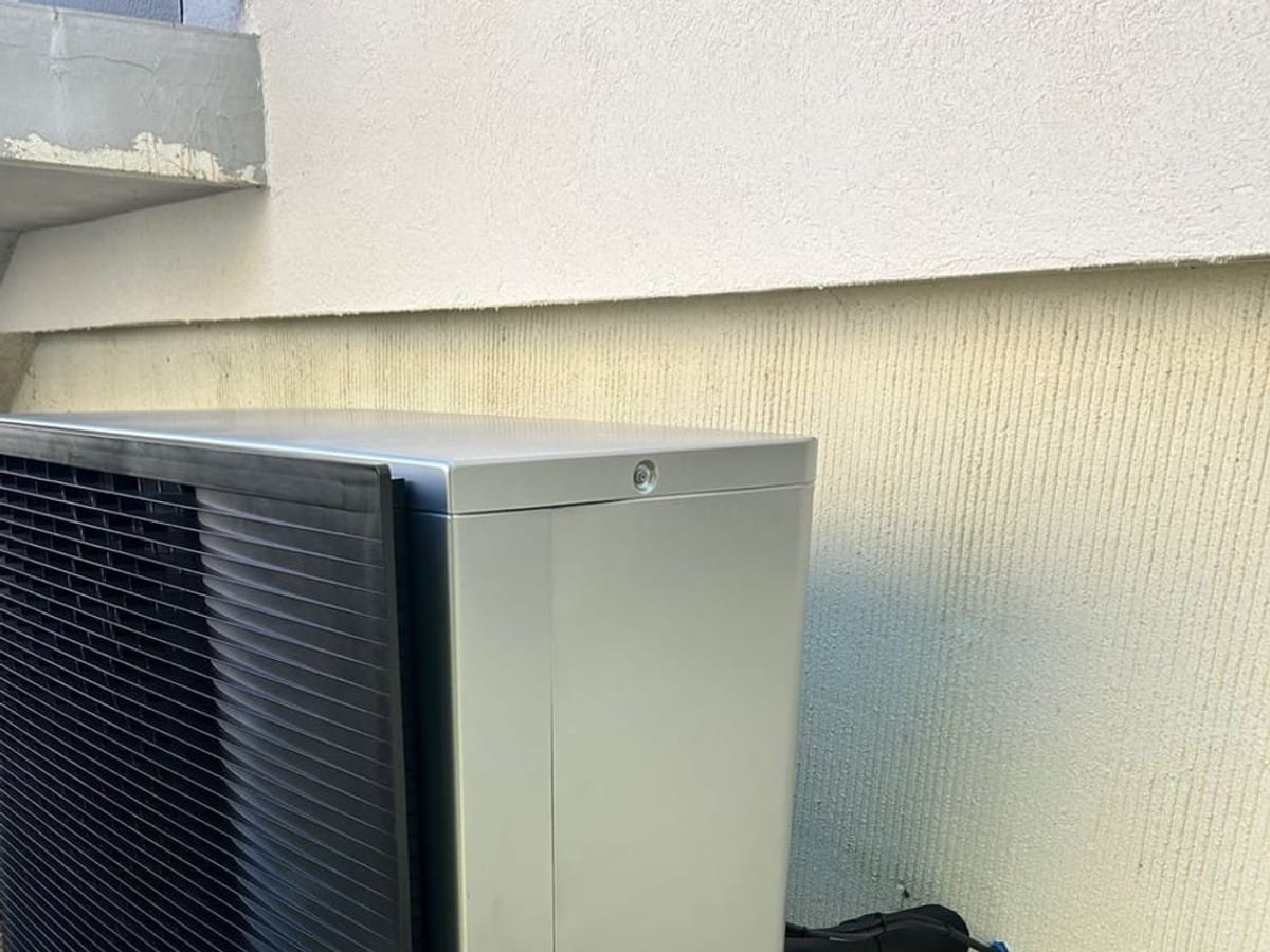 Unité extérieure de pompe à chaleur air-eau posée le long d'un mur, liaisons calorifugées